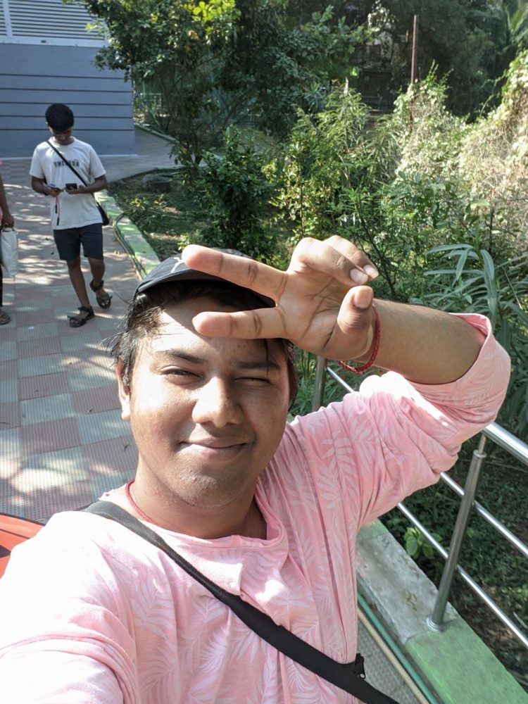 Selfie in a pink shirt shielding my eyes from the sun