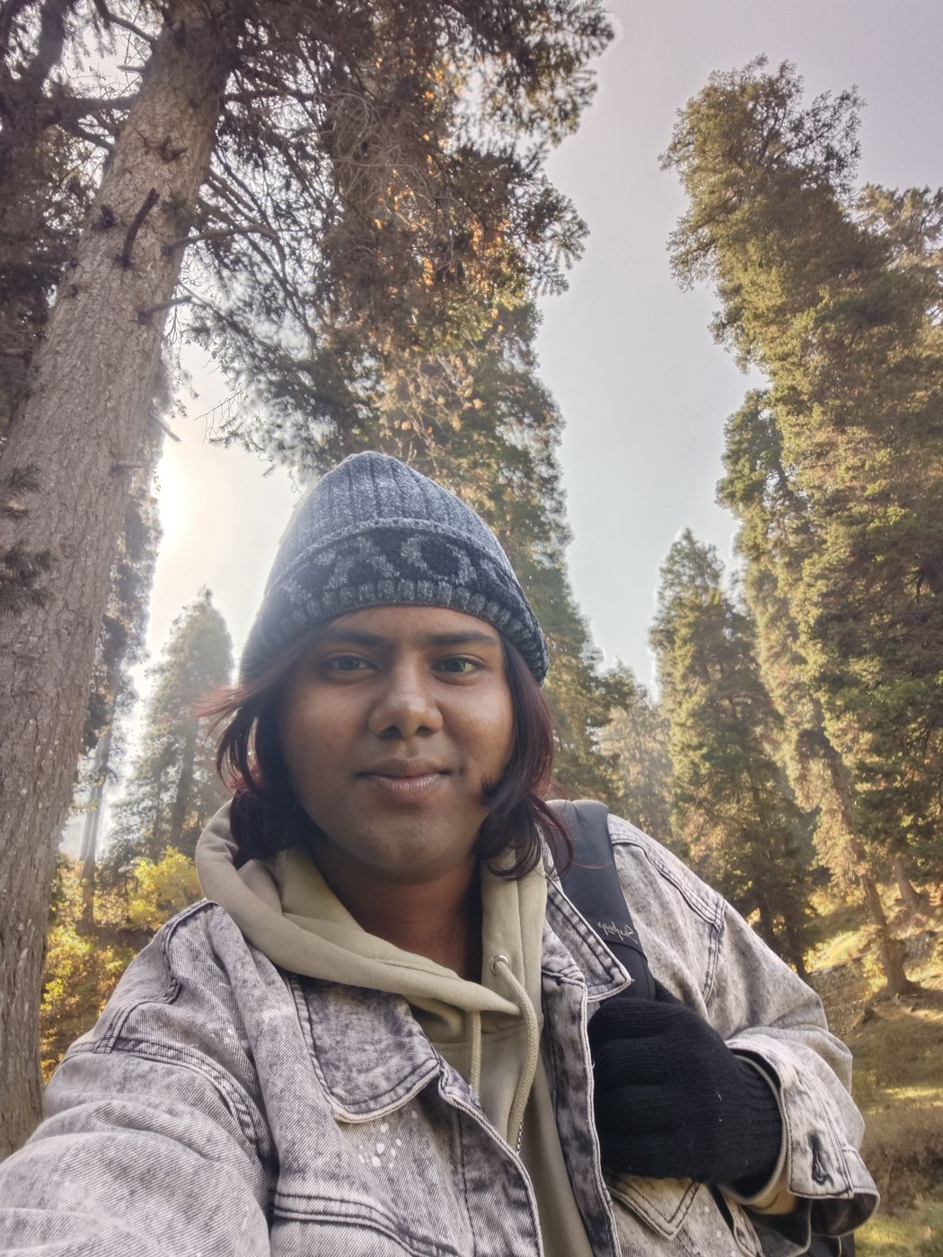 Selfie in a woollen cap among tall trees