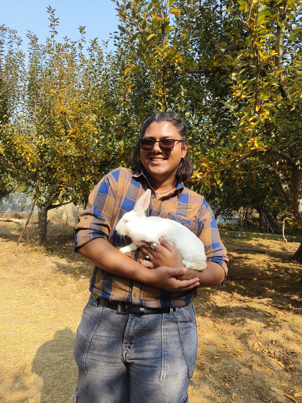 Holding a white rabbit in an orchard