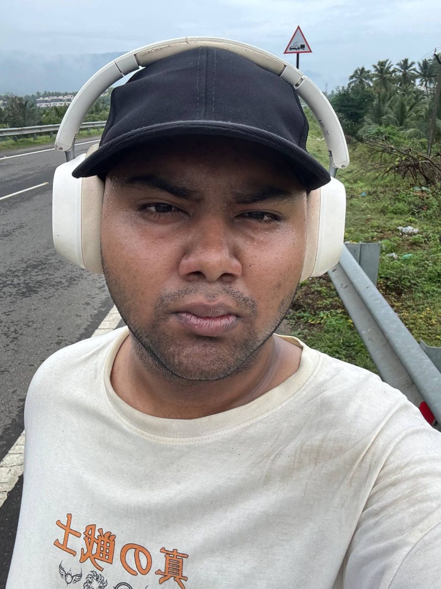 Selfie in a cap and white headphones on a roadside, looking serious