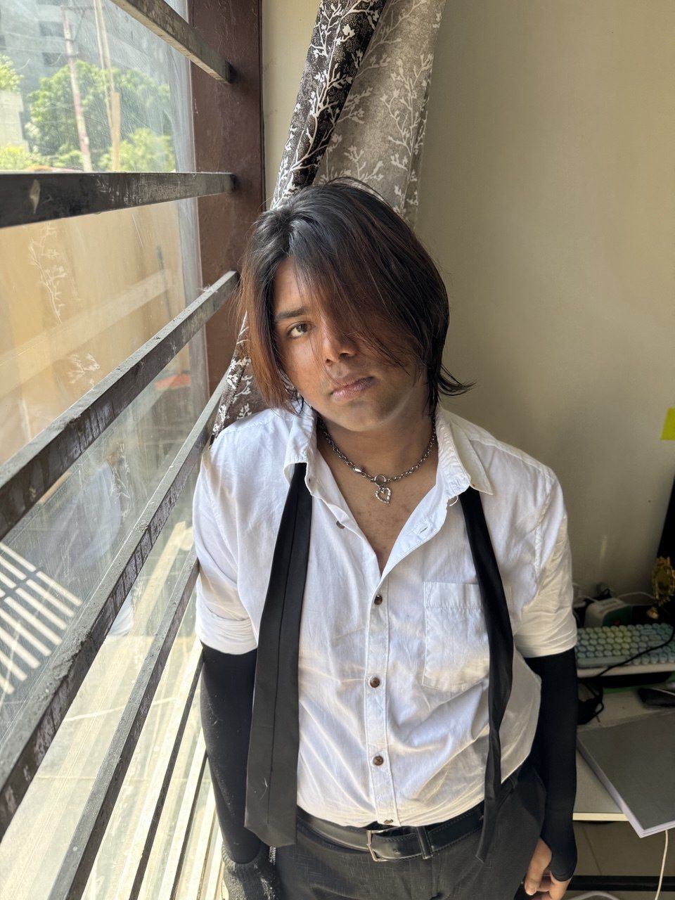 In a white shirt and black waistcoat by a window
